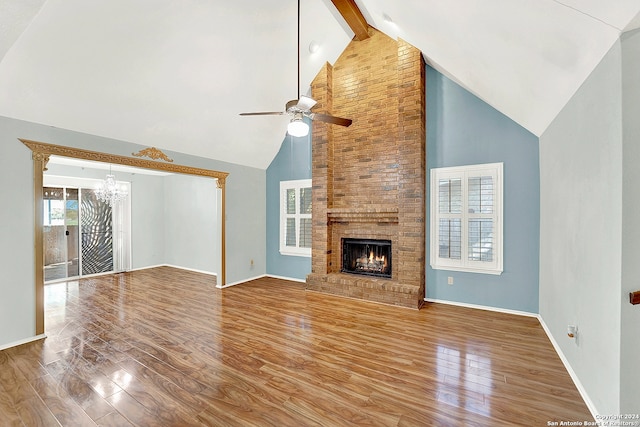 unfurnished living room with a brick fireplace, beam ceiling, hardwood / wood-style floors, and high vaulted ceiling