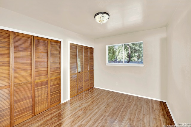 unfurnished bedroom with light wood-type flooring and two closets