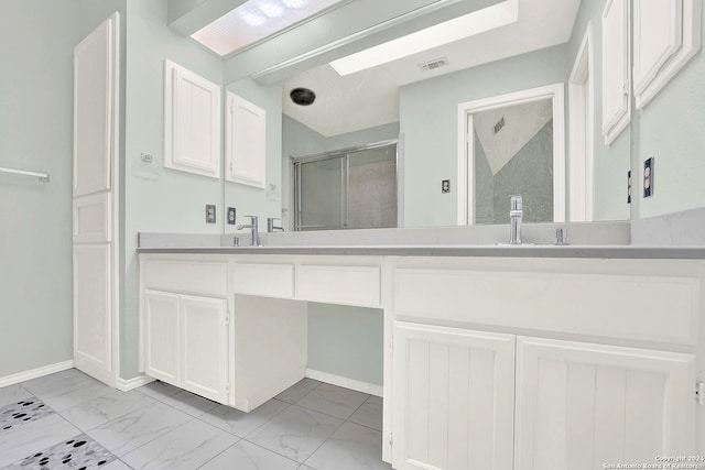 bathroom featuring a shower with shower door, vanity, and a skylight