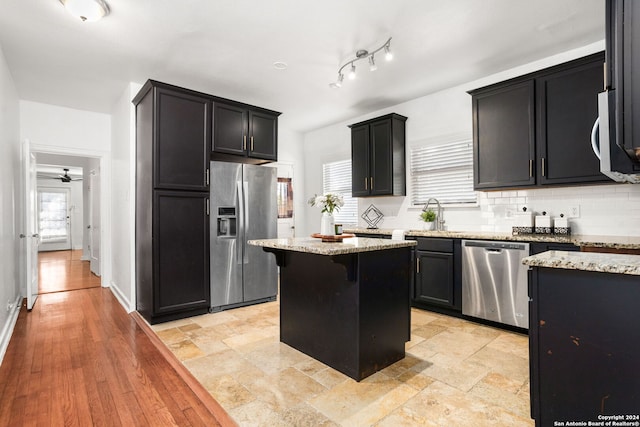 kitchen featuring a center island, light hardwood / wood-style flooring, light stone countertops, stainless steel appliances, and ceiling fan