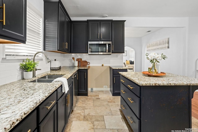 kitchen featuring appliances with stainless steel finishes, a kitchen island, decorative backsplash, and sink