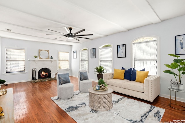 living room featuring a healthy amount of sunlight, ceiling fan, a brick fireplace, and wood-type flooring