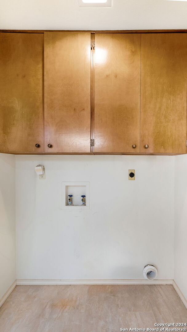 clothes washing area with hookup for a washing machine, cabinets, and hookup for an electric dryer