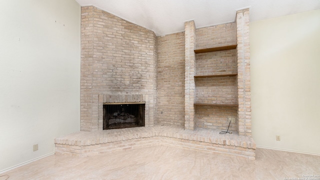 unfurnished living room with lofted ceiling, brick wall, a textured ceiling, and a brick fireplace