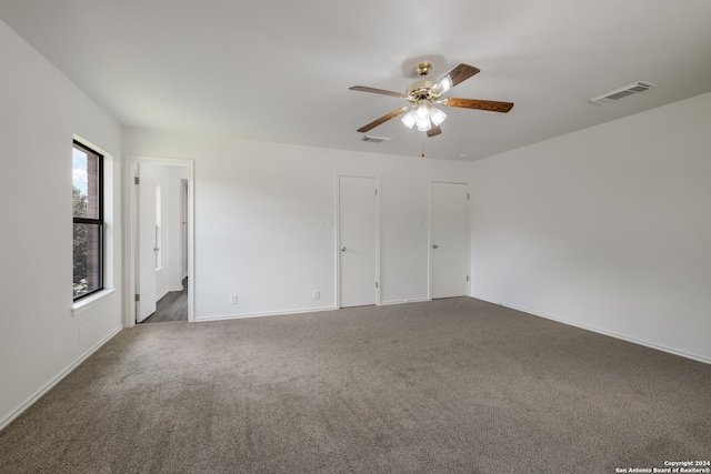 spare room with ceiling fan and dark colored carpet