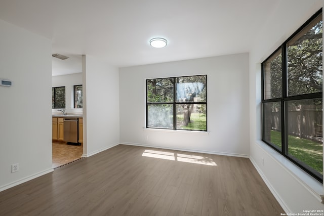 unfurnished room featuring hardwood / wood-style flooring, a wealth of natural light, and sink