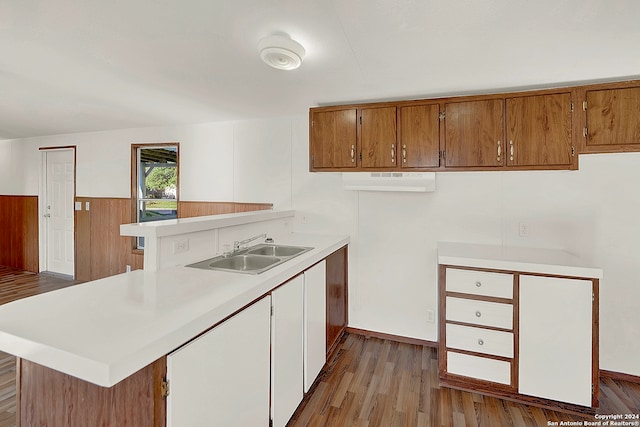 kitchen with light hardwood / wood-style floors, kitchen peninsula, and sink