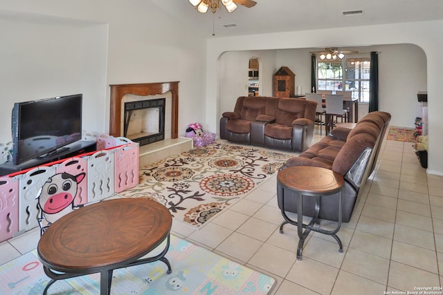 living room with ceiling fan, light tile patterned floors, and a tiled fireplace