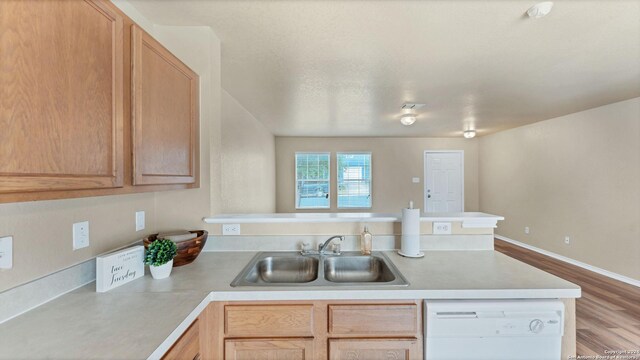 kitchen with dishwasher, light brown cabinetry, sink, and light wood-type flooring