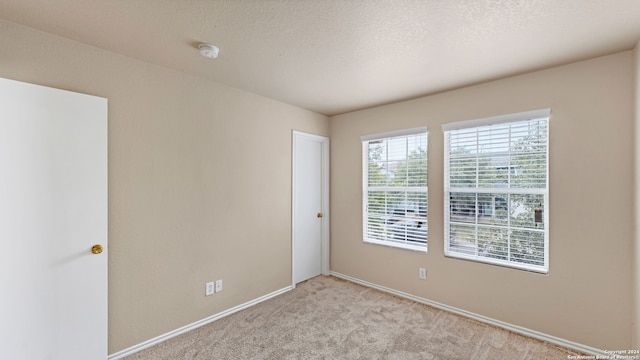 unfurnished room with a textured ceiling and light colored carpet