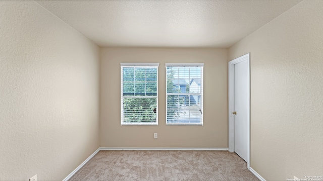 empty room with light carpet and a textured ceiling