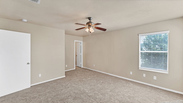 spare room with a textured ceiling, carpet flooring, and ceiling fan