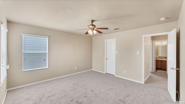 unfurnished bedroom with light colored carpet, ceiling fan, and a textured ceiling