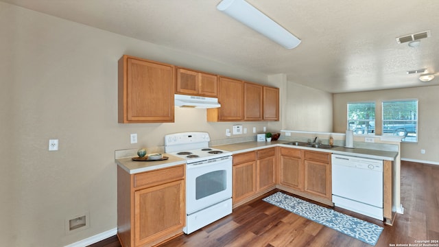 kitchen with a textured ceiling, white appliances, dark wood-type flooring, kitchen peninsula, and sink