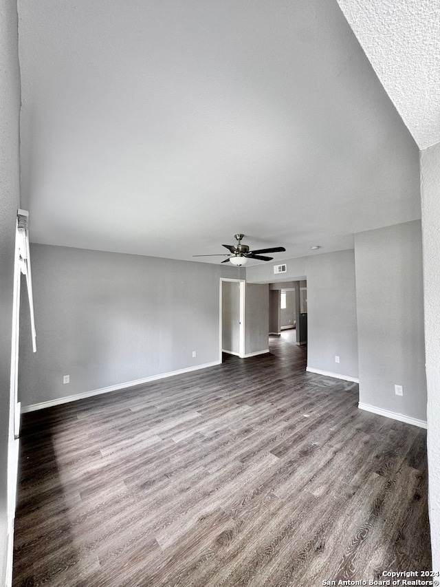 unfurnished living room featuring dark wood-type flooring, ceiling fan, and a textured ceiling