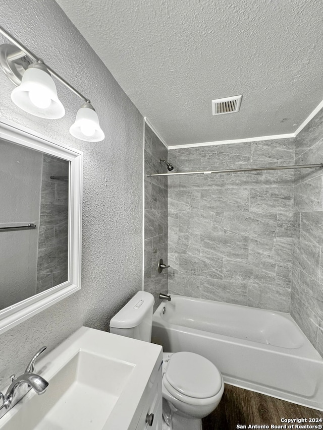 full bathroom featuring toilet, vanity, a textured ceiling, tiled shower / bath combo, and wood-type flooring