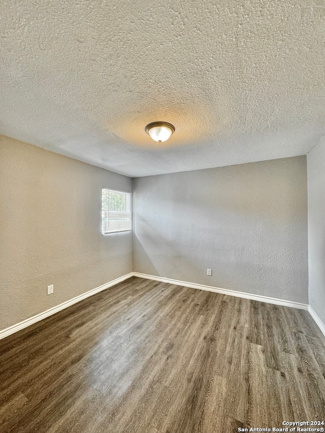 unfurnished room with a textured ceiling and hardwood / wood-style flooring