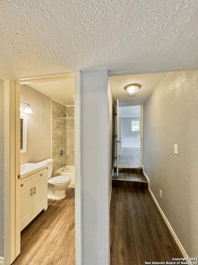 full bathroom with toilet, hardwood / wood-style floors, tiled shower / bath, vanity, and a textured ceiling