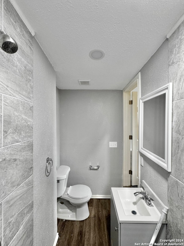 bathroom featuring a textured ceiling, vanity, wood-type flooring, walk in shower, and toilet