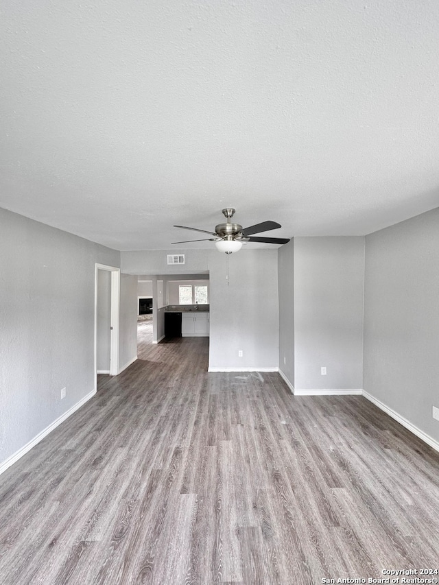 unfurnished living room featuring a textured ceiling, ceiling fan, and light wood-type flooring