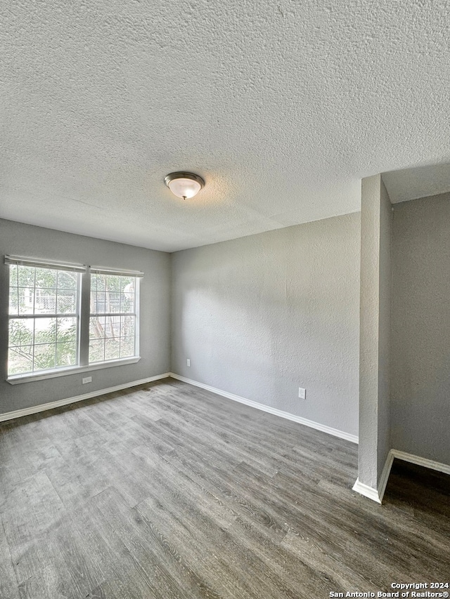 spare room with dark hardwood / wood-style flooring and a textured ceiling