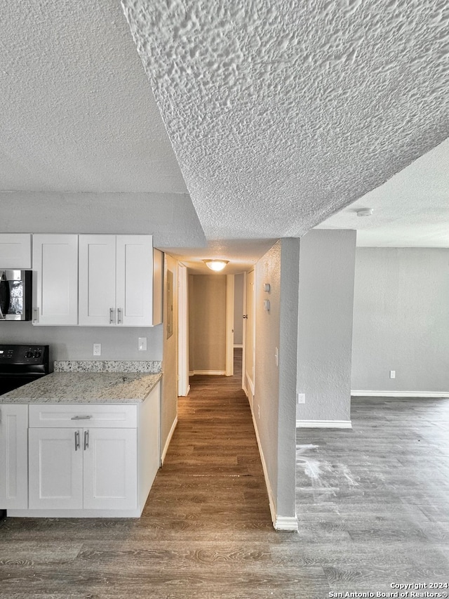 kitchen with black range with electric cooktop, a textured ceiling, light stone counters, white cabinets, and light hardwood / wood-style floors