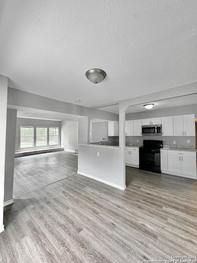 kitchen with light wood-type flooring, black range with electric cooktop, white cabinetry, a textured ceiling, and sink