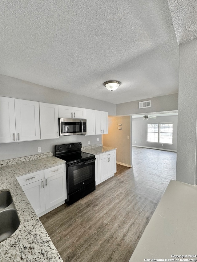 kitchen featuring white cabinets, wood-type flooring, black electric range oven, ceiling fan, and a textured ceiling