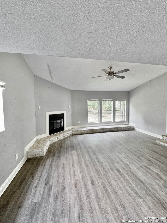 unfurnished living room with a textured ceiling, ceiling fan, hardwood / wood-style flooring, and lofted ceiling