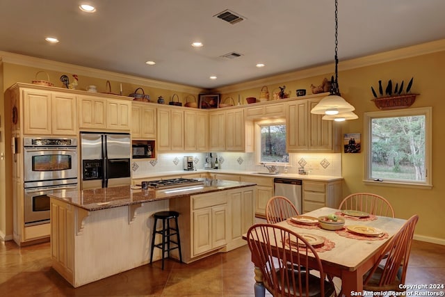 kitchen with a breakfast bar area, appliances with stainless steel finishes, dark tile patterned flooring, a center island, and sink