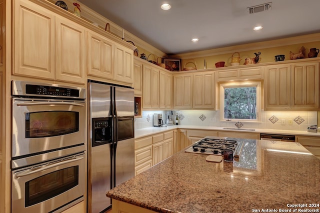 kitchen featuring stainless steel appliances, light stone countertops, decorative backsplash, and light brown cabinets