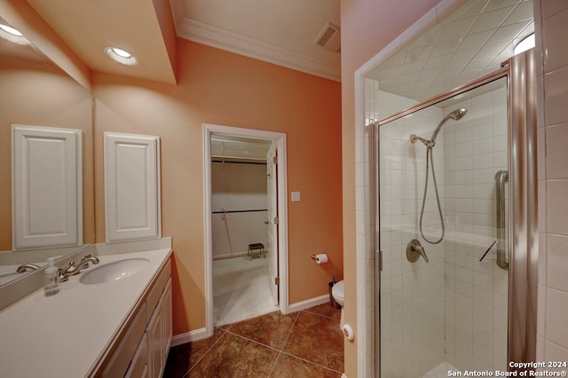 bathroom featuring toilet, tile patterned floors, a shower with door, crown molding, and vanity