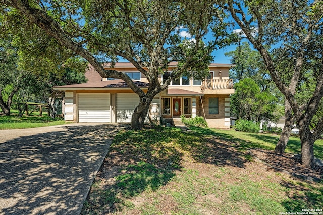 view of front of home with a garage, a balcony, and a front yard