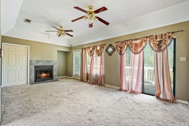 unfurnished living room with ceiling fan, a wealth of natural light, a fireplace, and carpet