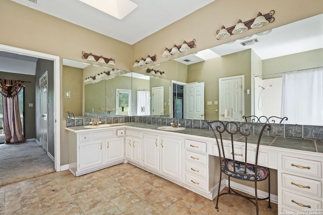 bathroom with a skylight, backsplash, a shower with shower curtain, and vanity