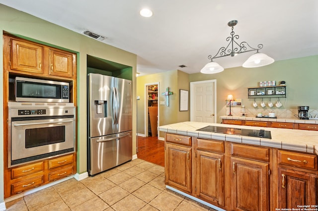 kitchen with pendant lighting, stainless steel appliances, light tile patterned floors, and tile countertops