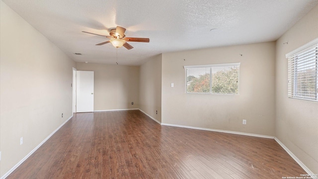 spare room with a textured ceiling, ceiling fan, a healthy amount of sunlight, and dark hardwood / wood-style floors