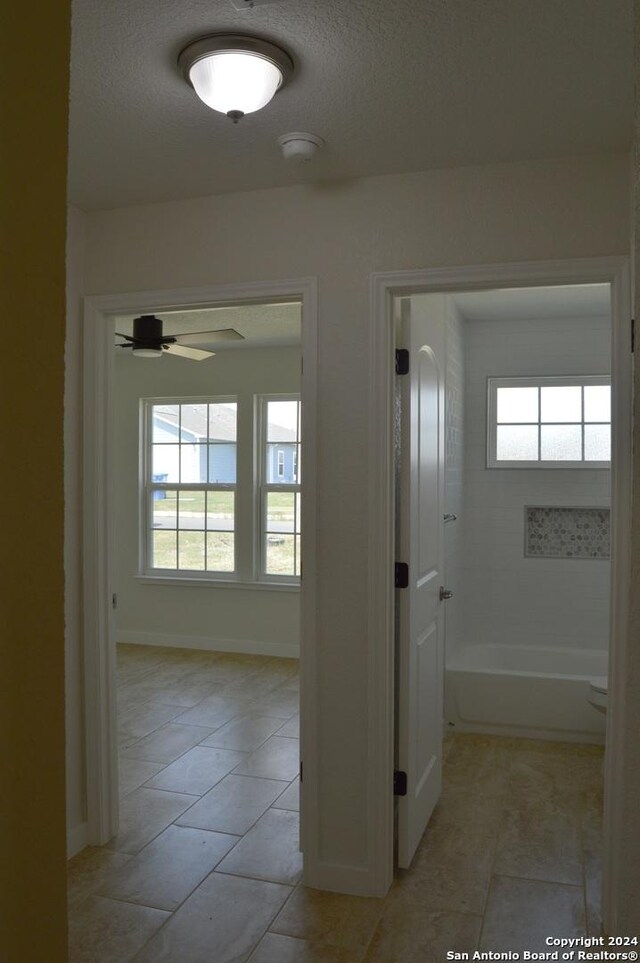 corridor with a textured ceiling and light tile patterned flooring