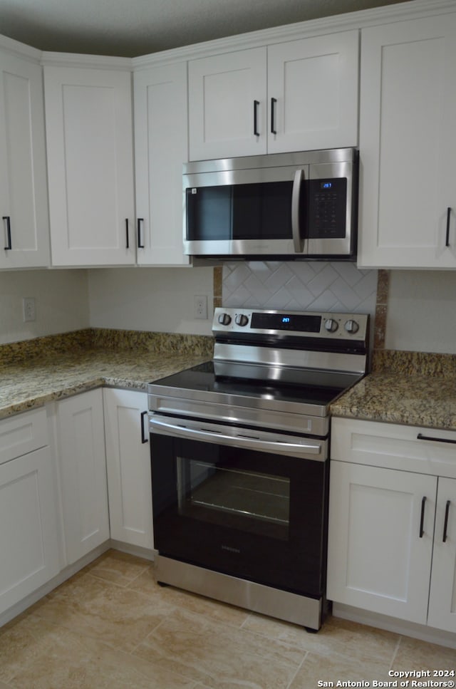 kitchen featuring stone counters, stainless steel appliances, and white cabinets