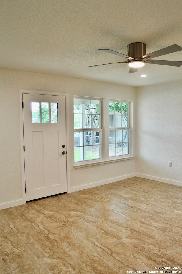 foyer entrance with a textured ceiling, plenty of natural light, and ceiling fan