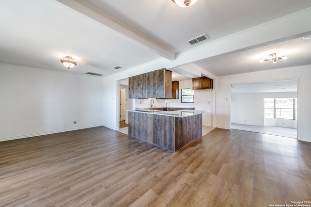 kitchen with wood-type flooring, a kitchen island, beamed ceiling, and a healthy amount of sunlight