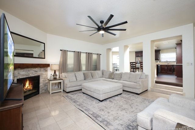 living room with a fireplace, ceiling fan, and sink