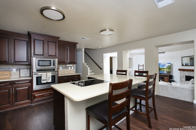 kitchen with stainless steel appliances, a kitchen bar, backsplash, and dark hardwood / wood-style flooring