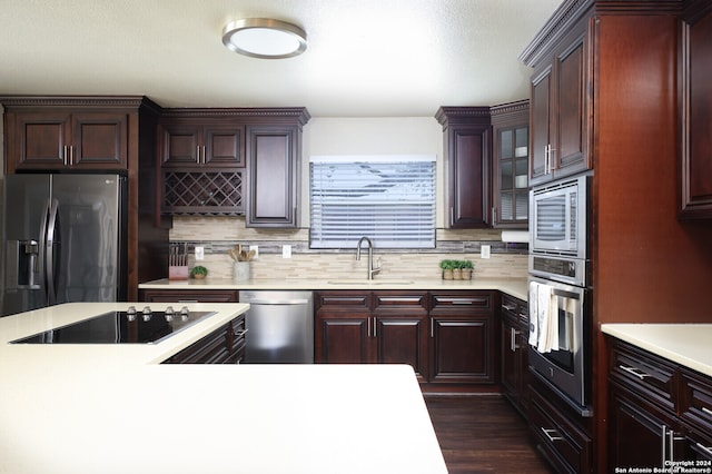 kitchen with dark wood-type flooring, sink, backsplash, and appliances with stainless steel finishes