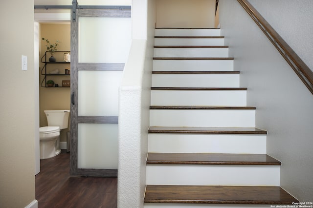 staircase featuring a barn door and hardwood / wood-style flooring