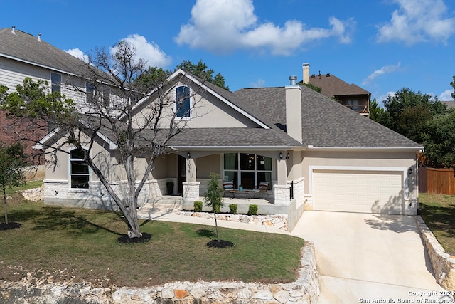 view of front of property featuring a garage, a front yard, and a porch