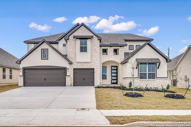 french country inspired facade featuring stone siding, an attached garage, driveway, and a front yard