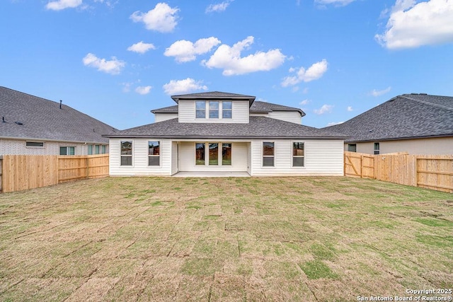 back of house with a yard, a fenced backyard, and roof with shingles