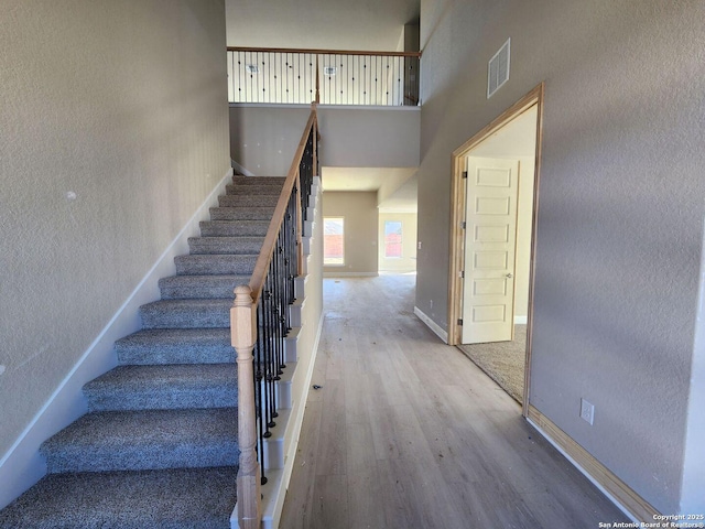 staircase with hardwood / wood-style flooring and a high ceiling