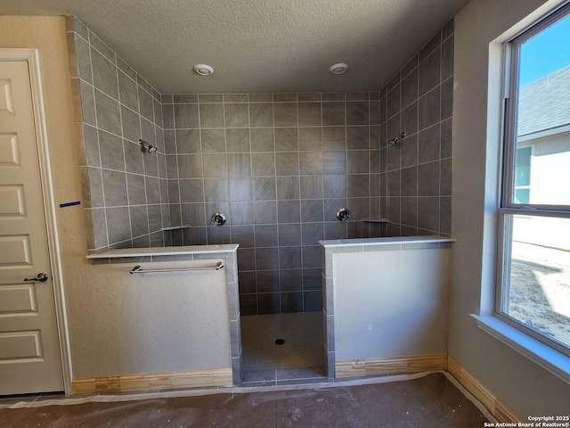 bathroom with a tile shower and a textured ceiling